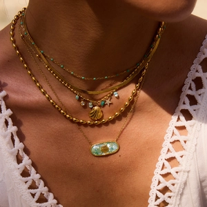 Detailed shot of layered gold ocean-themed necklaces with shell and starfish charms