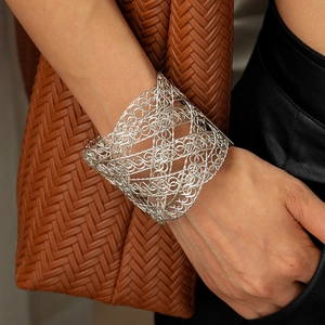 Detailed close-up of wide silver mesh cuff bracelet with intricate filigree texture
