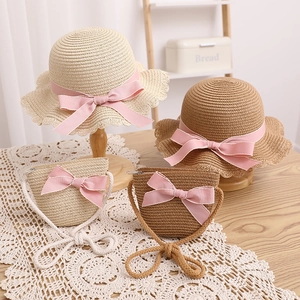 Détail d'un chapeau de paille et d'un sac assorti avec des nœuds roses pour enfant