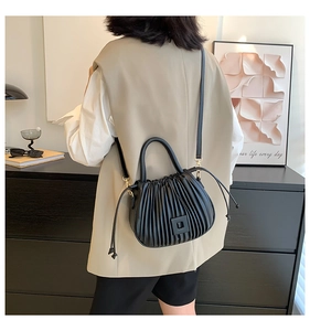 Close-up of black pleated leather bucket bag with metallic magnetic clasp and handle