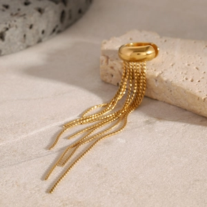 Detailed close-up of a gold tassel ear cuff on a stone surface with soft lighting