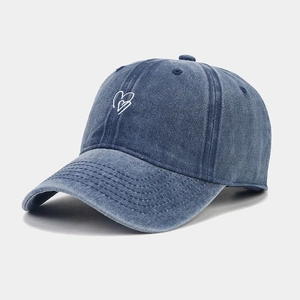 Vue détaillée de la broderie cœur blanc sur casquette de baseball en jean bleu délavé