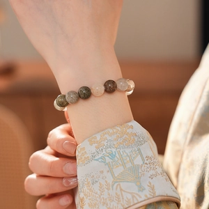 Détail d'un bracelet en quartz rutilé coloré porté au poignet avec broderie élégante