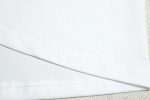 Detailed close-up of double-stitched hem and sewing craftsmanship on a white dress