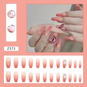 Détail de faux ongles dégradé rose avec strass en cœur 3D et forme ballerine