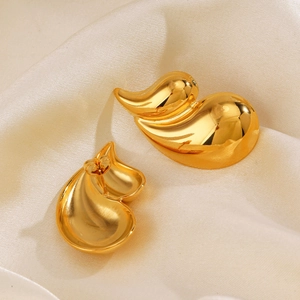Polished 18K gold-plated stainless steel teardrop earrings on beige silk fabric