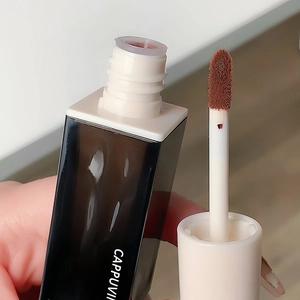 Glossy red brown velvet lip glaze with a plush applicator in a sleek black and white bottle