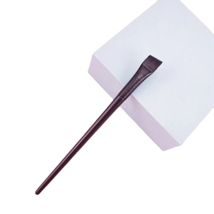 Fine blade eyeliner brush with ultra-thin bristles on a minimalist white cube pedestal