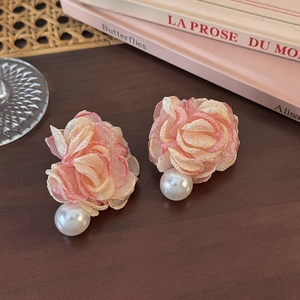 Detail showing pink chiffon flower earrings with pearls on a vintage wooden desk