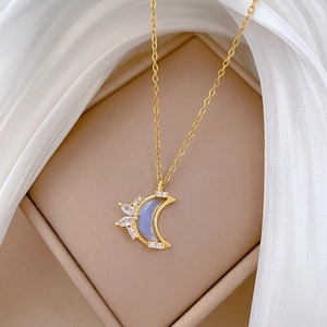 Macro shot of a gold crescent moon pendant with blue shimmer and small clear crystals