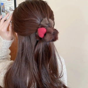 Détail d'un chouchou en peluche marron orné d'un cœur rouge sur cheveux