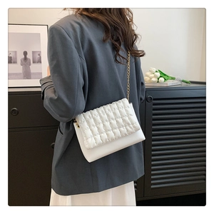 Rear view of model wearing white quilted crossbody bag with golden chain strap