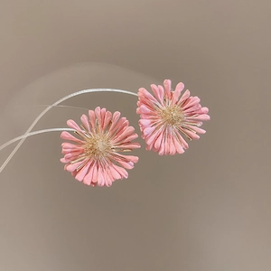 Detailed view of pink raffia daisy stud earrings with golden floral stamens