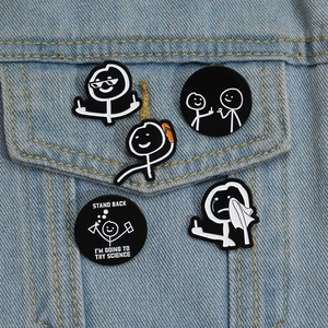 Detailed close-up of funny stickman enamel pins on a blue denim jacket pocket
