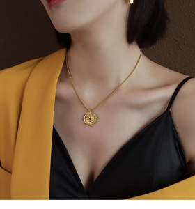 Detail of a vintage 18k gold irregular geometric coin pendant necklace worn by a model