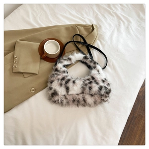 Detail of plush crescent bag with cow print pattern on minimalist beige fabric background