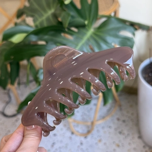 Detail of 14cm dusty pink claw clip being held to show large size and glossy finish