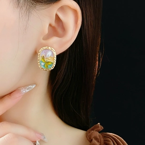 Detailansicht der Vintage-Ohrringe mit Emaille-Blumen und Perlen am Modelohr