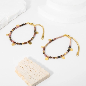 Dettaglio del bracciale di perle colorate in acciaio inossidabile con dischi dorati e tag