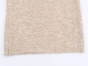 Dettaglio ravvicinato della maglia color avena con trama fine e orlo a costine