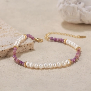 Elegant bracelet with freshwater pearls and purple stones on a textured stone surface