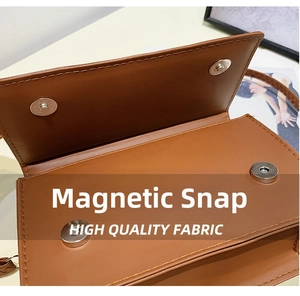 Close-up of the silver magnetic closure on a brown leather crossbody bag with stitching