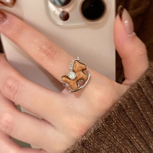 Macro detail of silver rocking horse ring with zircon accents and brown wood-like inlay