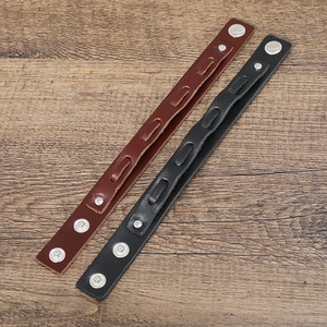 Detailed view of layered brown and black leather bracelets with silver metal snap buttons