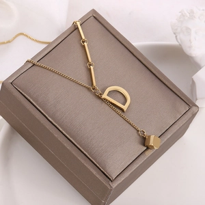 Detailed view of an 18K gold-plated titanium necklace with a D letter and cube pendant