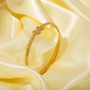 Luxury gold H-letter bangle with sparkling cubic zirconia on a silk background