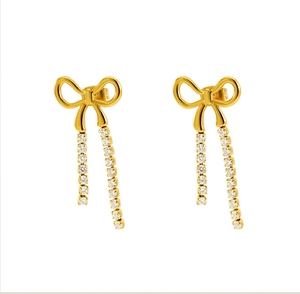 Detail of golden bow earrings featuring long tassels set with sparkling clear gemstones