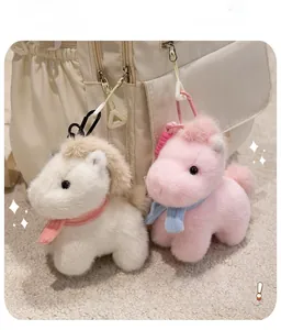 Close-up of cute plush horse keychains with knit scarves on a cream backpack