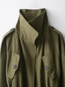 Detail view of army green cotton trench coat showing epaulets and twill fabric texture