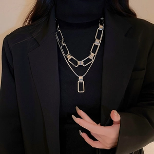 Close-up of double layered silver metal chain necklace with geometric pendant on model