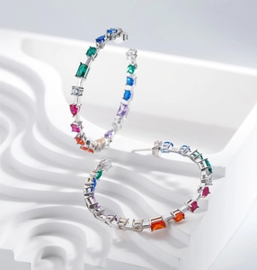 Macro shot of 925 silver hoop earrings with multi-colored gemstones in geometric cuts