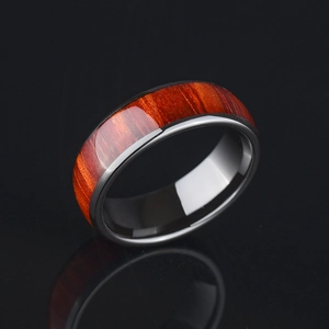 Polished black ring with red-brown wood inlay grain on a reflective dark surface