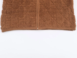 Dettaglio del cardigan in peluche marrone con texture in pelliccia e zip sul bordo
