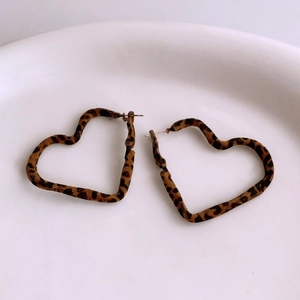 Macro view of heart-shaped leopard print earrings with soft velvet texture on white plate