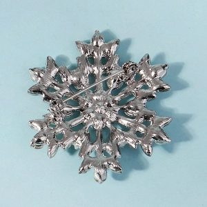 Macro shot of silver snowflake brooch back showing durable metal safety pin closure