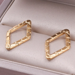 Macro shot of geometric gold earrings with textured bamboo-like surface details