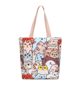 Close-up of pink handles and colorful cartoon cat pattern on a canvas tote bag