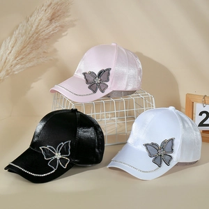 Detail of satin baseball caps in pink, black, and white with rhinestone butterfly accents