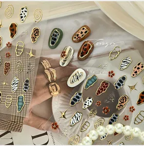 Detail of French animal print nail stickers with gold accents and 3D metal charms