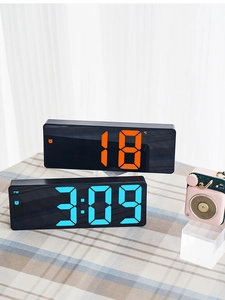 Close-up of LED digital alarm clocks showing temperature and time in orange and blue