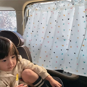 Car window sunshade with geometric triangle pattern protecting a child in a car seat