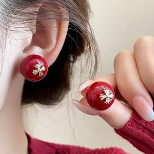 Elegant red spherical stud earrings with golden cross pattern for a festive New Year look