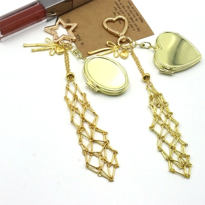 Detailed view of golden mesh pendant keychains with oval and heart lockets on a white background