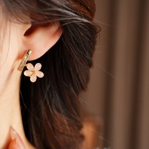 Close-up of pink resin flower earring with zircon inlay on a model's ear