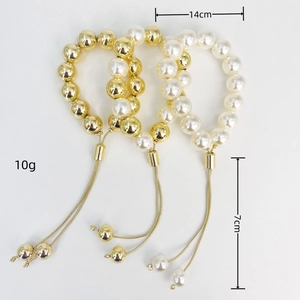 Detailed view of three-piece stretch beaded bracelets with golden tassels and pearls