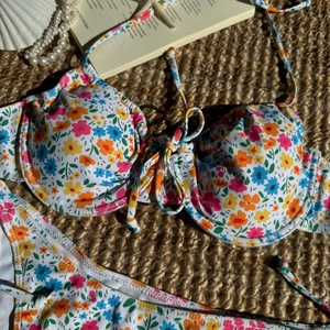 Flachbild von Bikini mit Blumendruck, Schleifendetail und Stahlring auf Strohmatte